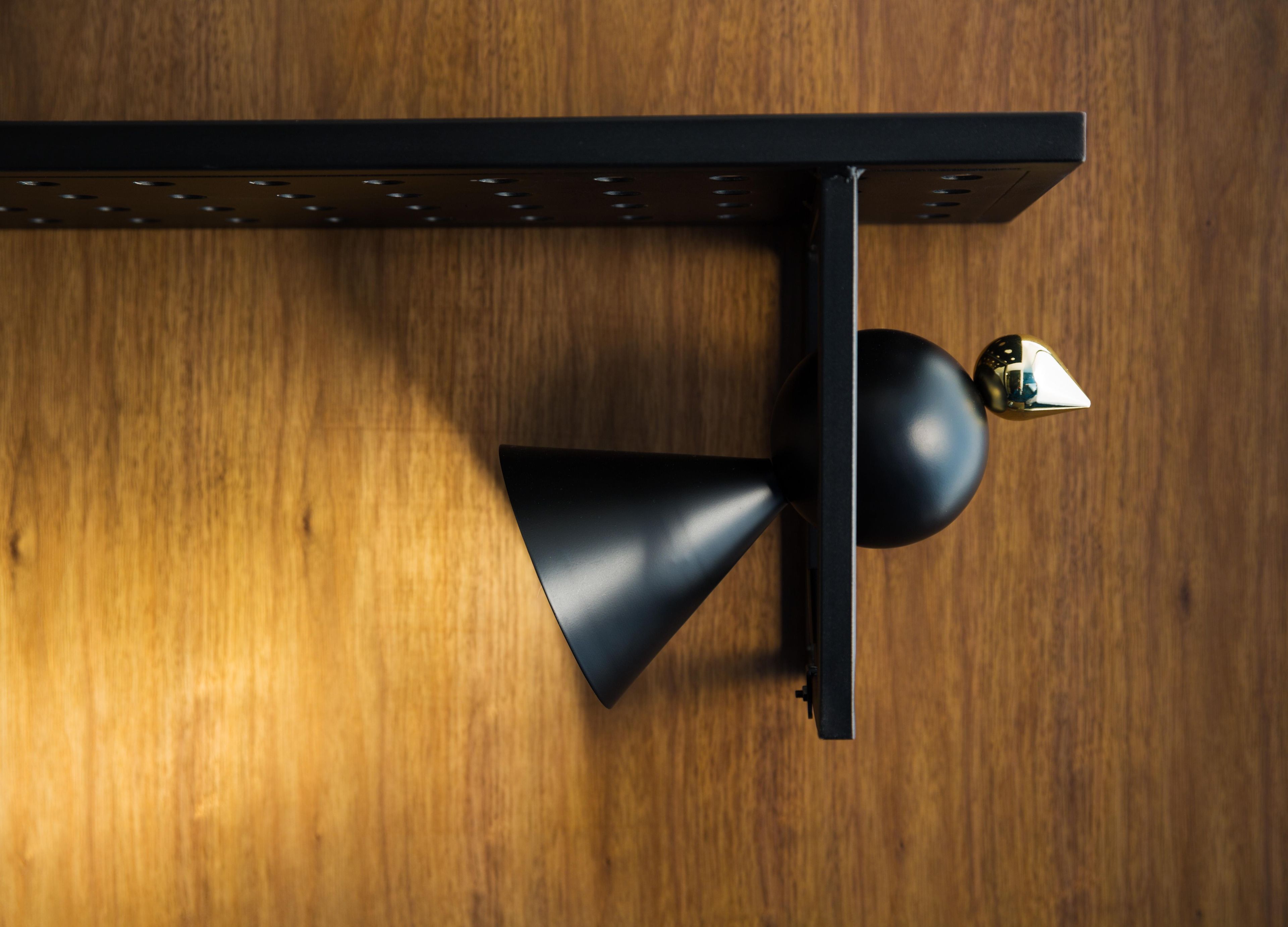 A black ceiling-mounted light fixture with a spherical accent on a wooden floor.