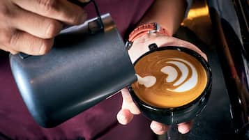 A person holding a cup of coffee with latte art.