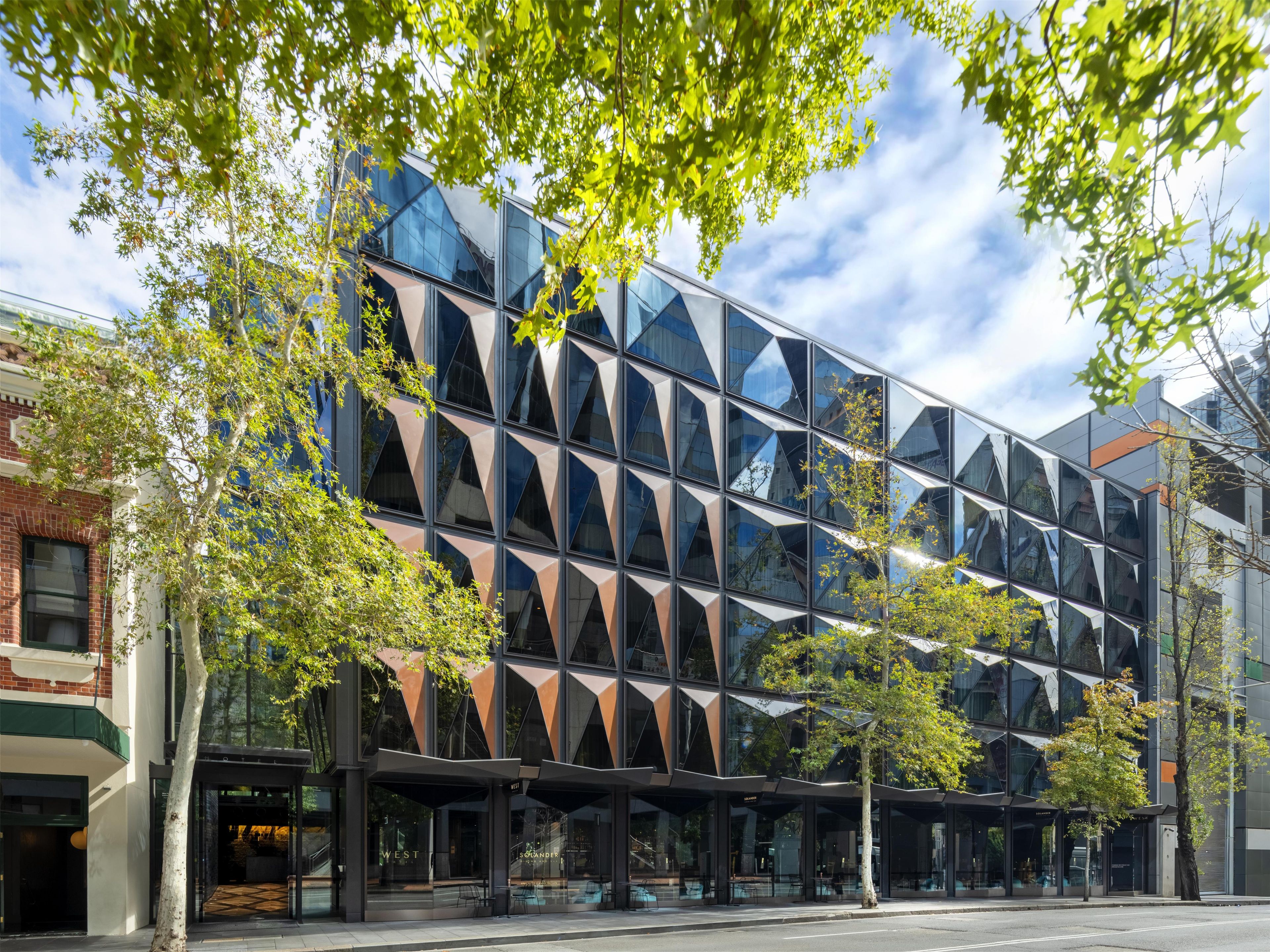 A modern building with a glass facade, a brick base, and a covered entrance area.