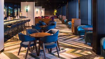 Een moderne lounge met een bar, tafels en stoelen.