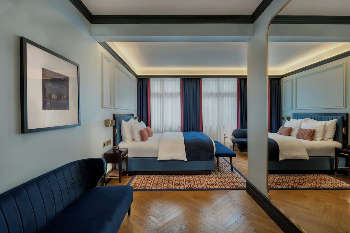 Et hotelværelse med en stor seng, en sofa, et skrivebord og et spejl.