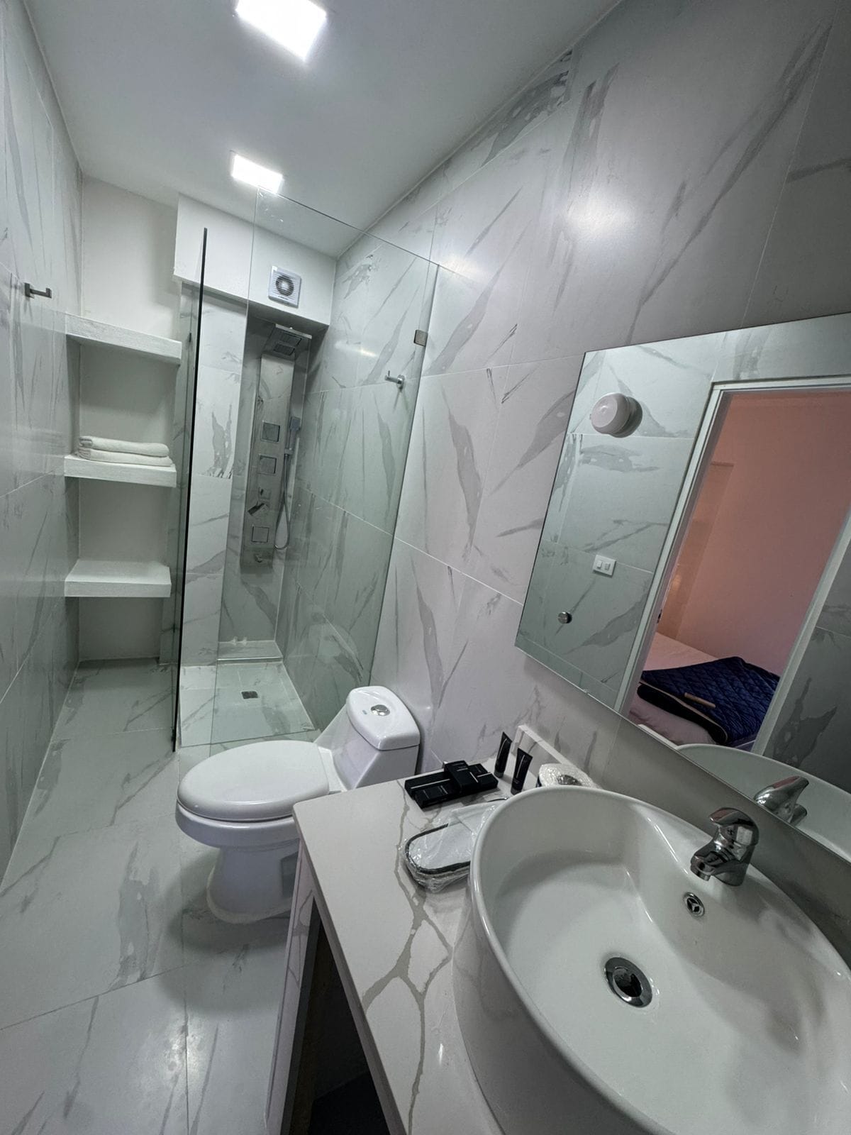A modern bathroom with a toilet, sink, and glass shower enclosure.