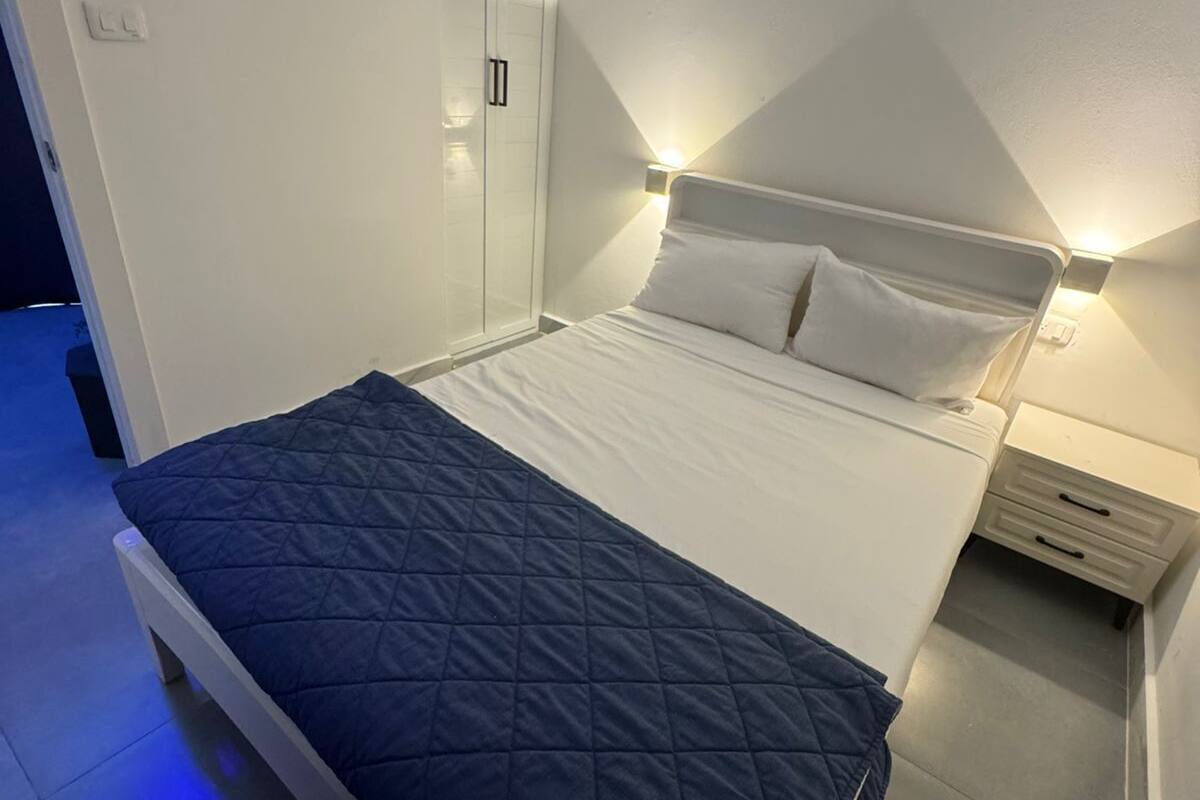 A bedroom with a bed, bedside tables, a wardrobe, and a wall-mounted light fixture.