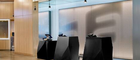 A modern reception area with three black podiums, wooden paneling, and a patterned wall.