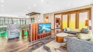 A spacious lobby with a large TV, comfortable seating, and a view of the outdoors through large windows. - Courtyard by Marriott Longview North (Longview)