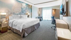 A hotel room with a large bed, a desk, a chair, a TV, and a painting on the wall. - Courtyard by Marriott Longview North (Longview)