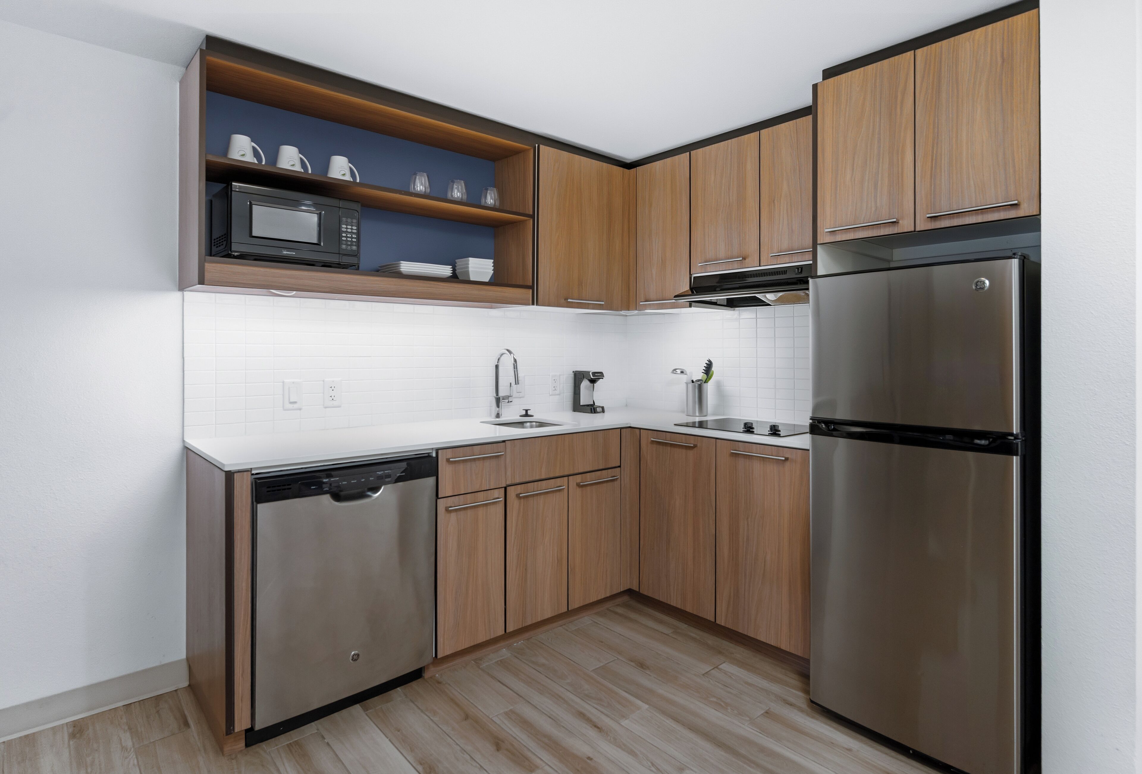 Una cocina moderna con armarios de madera, un refrigerador de acero inoxidable, un microondas y un lavavajillas.