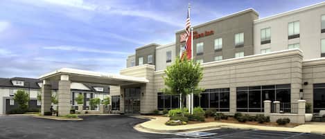 A hotel with a parking lot, a flag, and a building entrance.