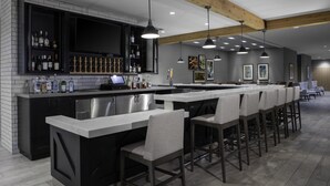 A modern kitchen with a bar area, stainless steel appliances, and a long counter with bar stools. - Hilton Garden Inn Jackson (Jackson)