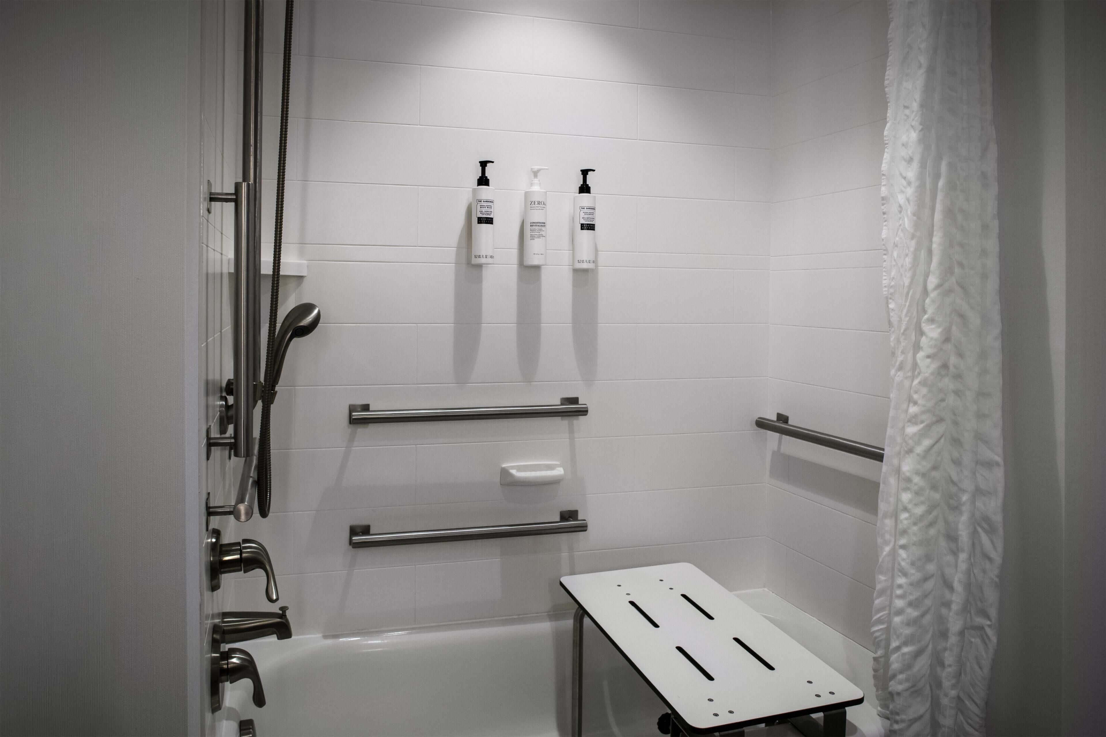 Un baño moderno con bañera, ducha y barras de apoyo.