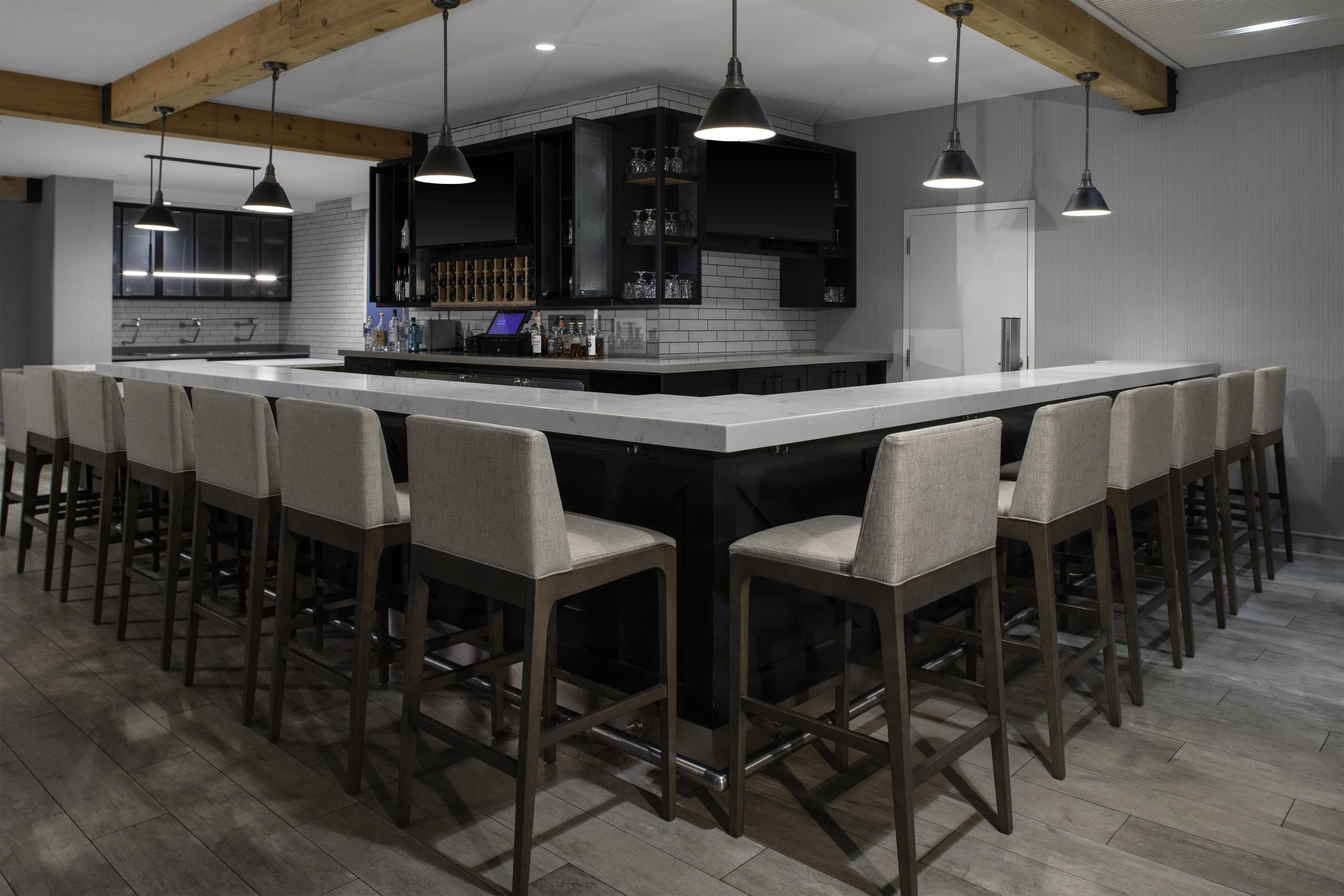 A modern kitchen with a large island, bar stools, pendant lighting, and built-in appliances.