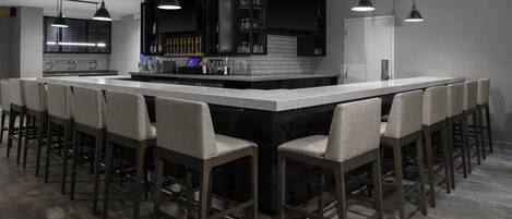 A modern kitchen with a large island, bar stools, pendant lighting, and built-in appliances.