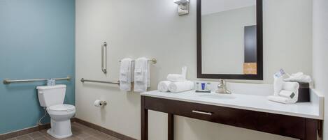 A bathroom with a toilet, sink, mirror, and towel rack.