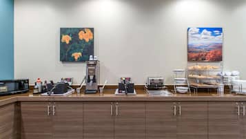 Zona de desayuno de hotel con cafetera, tostadora y exhibición de pan.