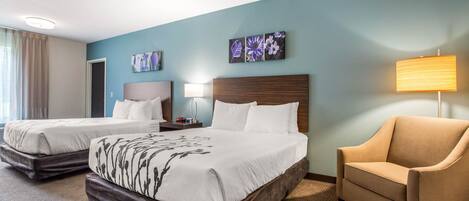 A hotel room with two beds, a sofa, and artwork on the walls.