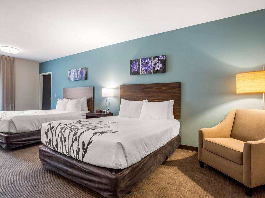 A hotel room with two beds, a sofa, and artwork on the walls.