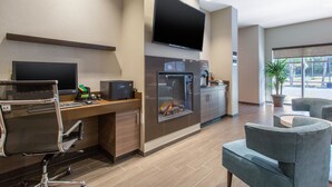 Een moderne hotelkamer met een flatscreen-tv, een open haard, een bureau met een computer en comfortabele zithoek.