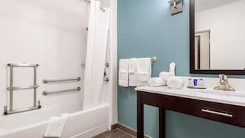Un baño con bañera, lavamanos, espejo y toallero.