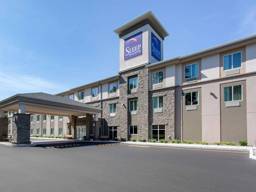 Edificio de Sleep Inn & Suites con entrada cubierta, fachada de piedra y numerosas ventanas.