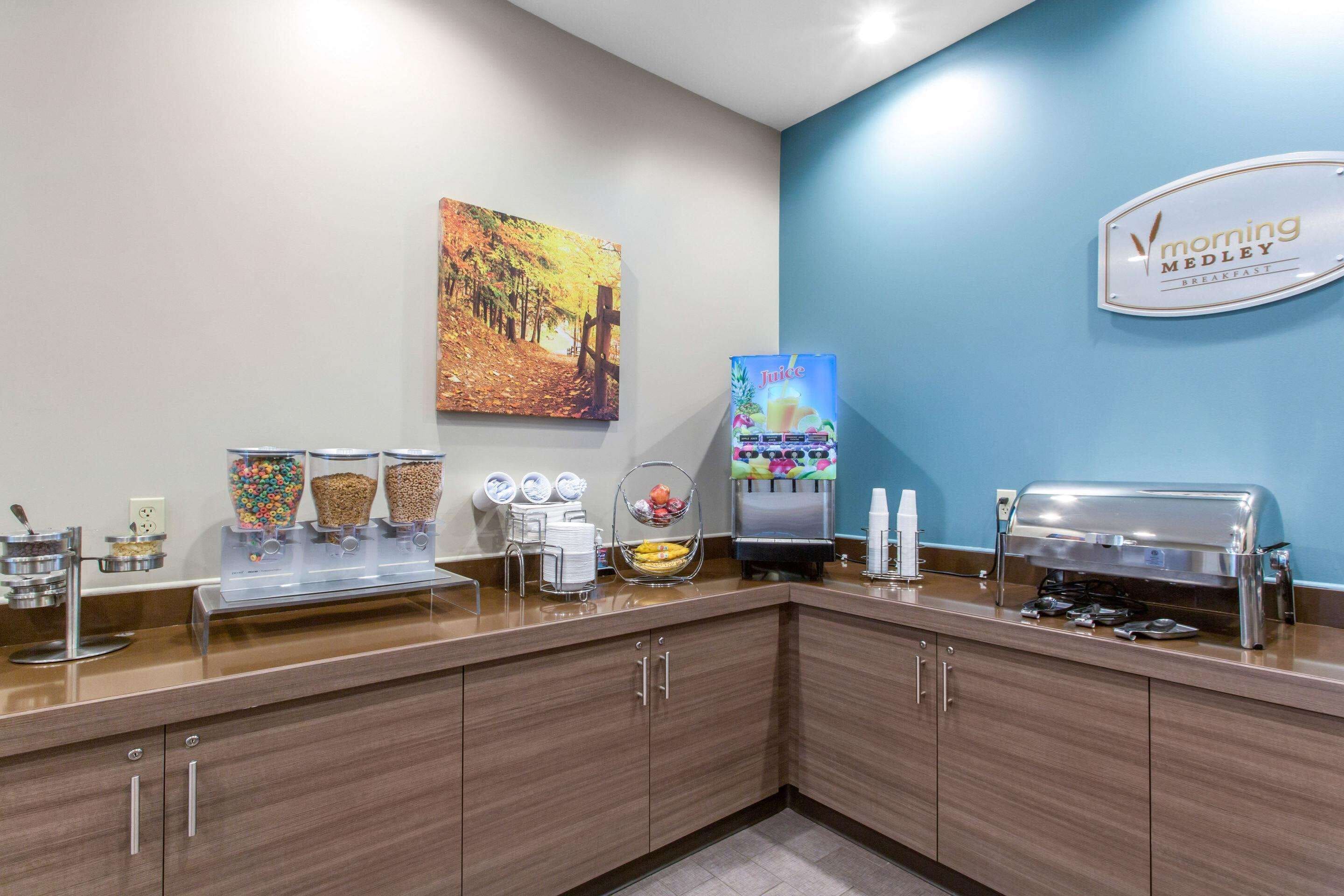 A breakfast area with a juice dispenser, coffee machine, and a sign for 'Morning Medley Breakfast'.
