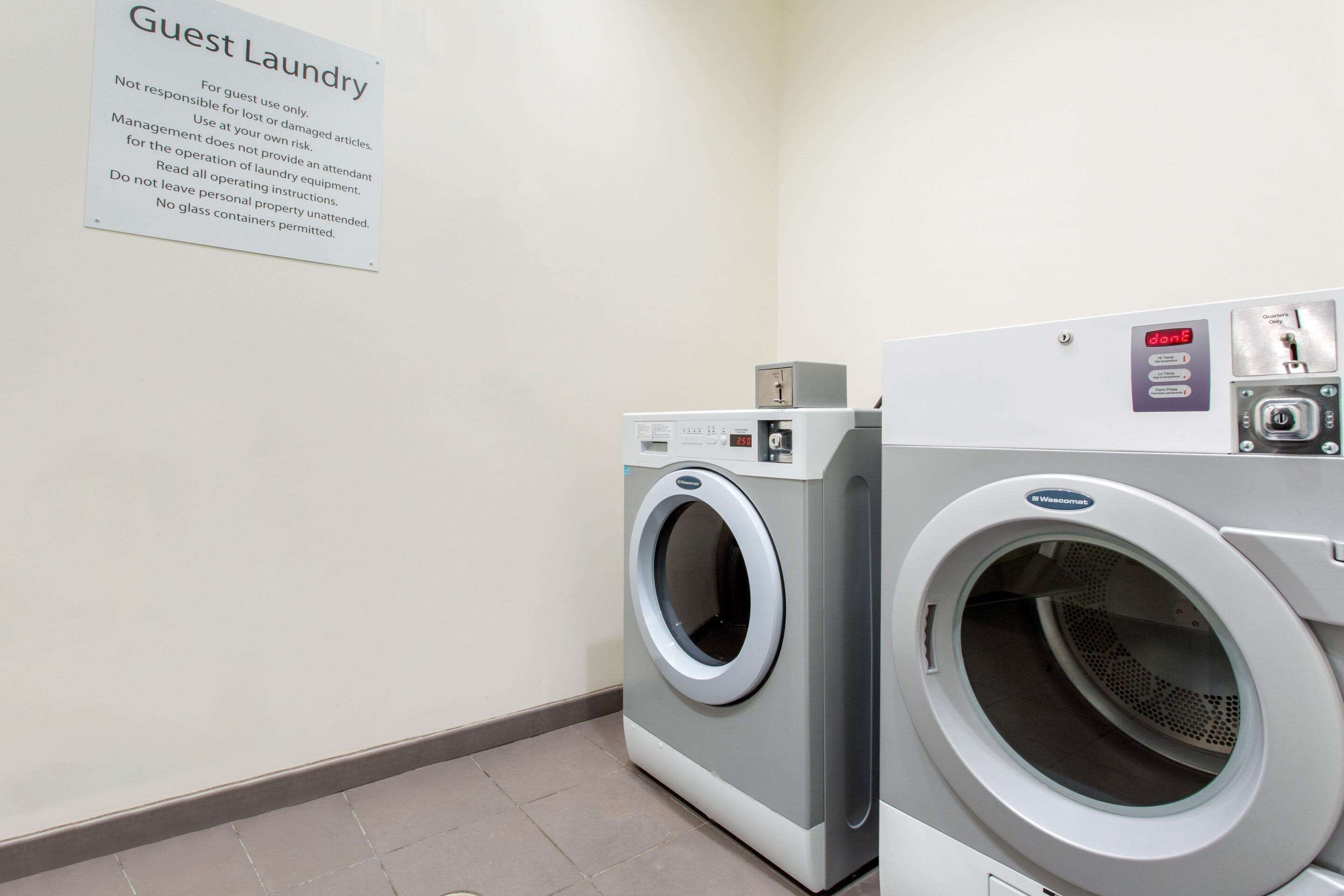 A guest laundry area with a sign detailing usage rules and two front-loading washing machines.