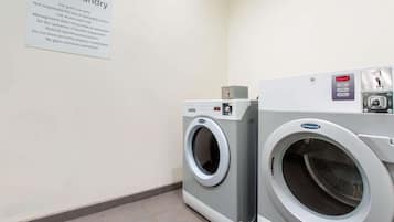 A guest laundry area with a sign detailing usage rules and two front-loading washing machines.