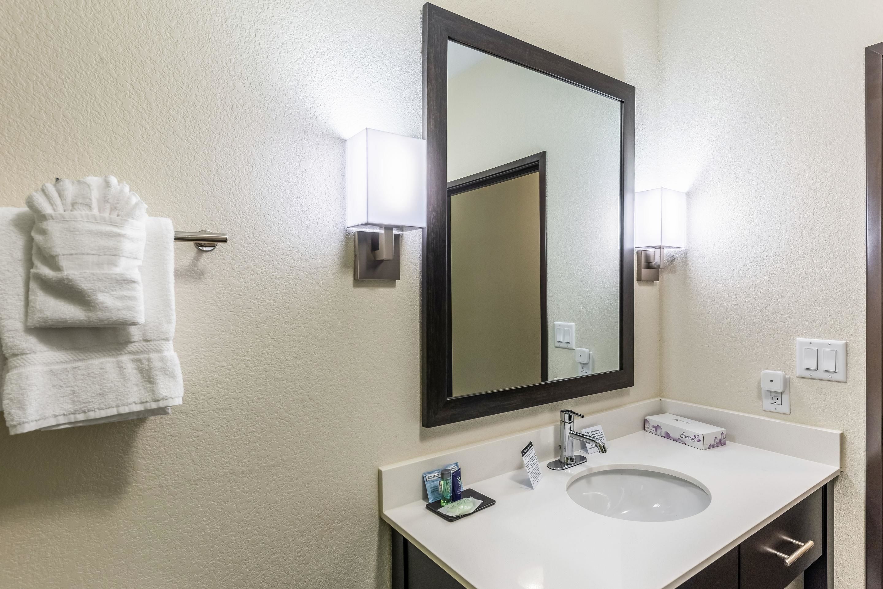A hotel bathroom with a white sink, a large mirror, and a towel rack.