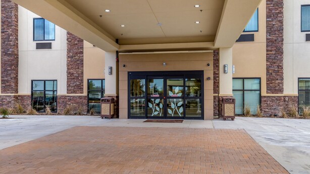 A building entrance with a brick pathway leading to a glass door with a leaf design. - Sleep Inn & Suites Fort Worth - Fossil Creek (Fort Worth)