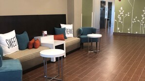 A modern lounge area with a sofa set, two round tables, and a wall with a floral design. - Sleep Inn & Suites Fort Worth - Fossil Creek (Fort Worth)