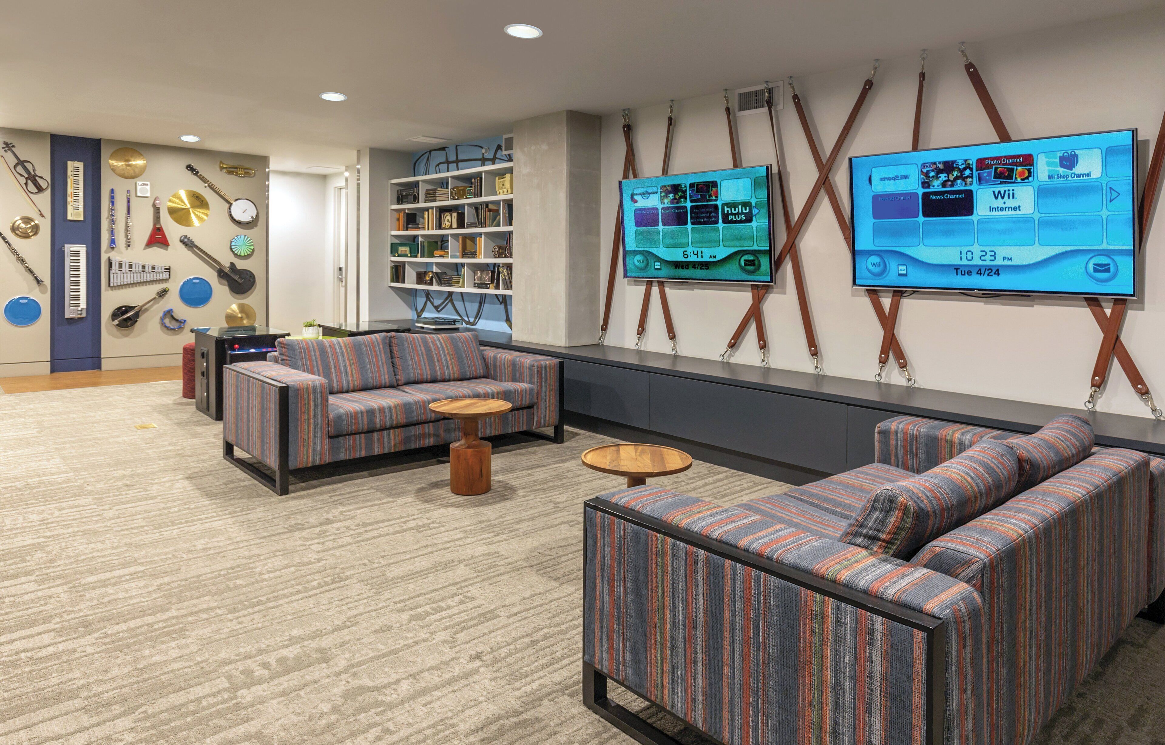 A modern lounge area with striped sofas, a bookshelf, and a large TV displaying a digital interface.