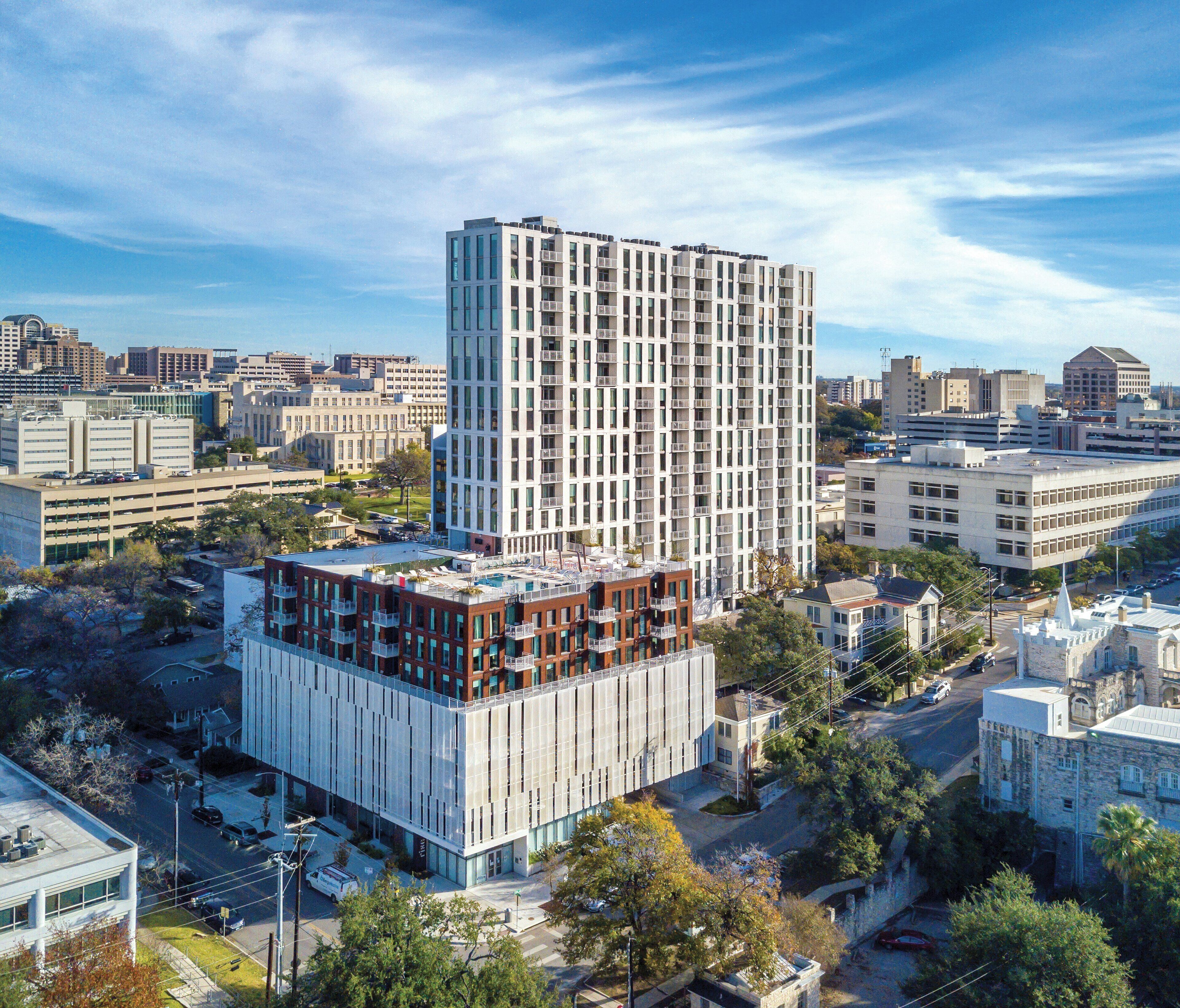 A high-rise building with a modern architectural design, featuring multiple balconies and a mix of glass and concrete facades.