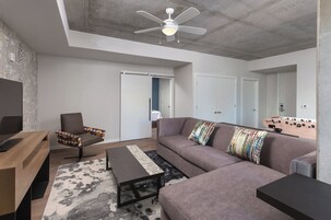 Una sala de estar moderna con un sofá, un sillón, una mesa de centro y una mesa de futbolín.