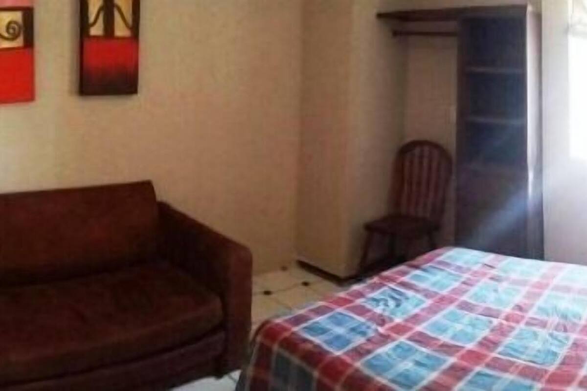 Un dormitorio con cama, sofá, armario y dos cuadros.