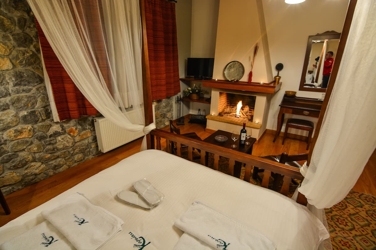 A hotel room with a bed, a fireplace, a television, and a mirror.