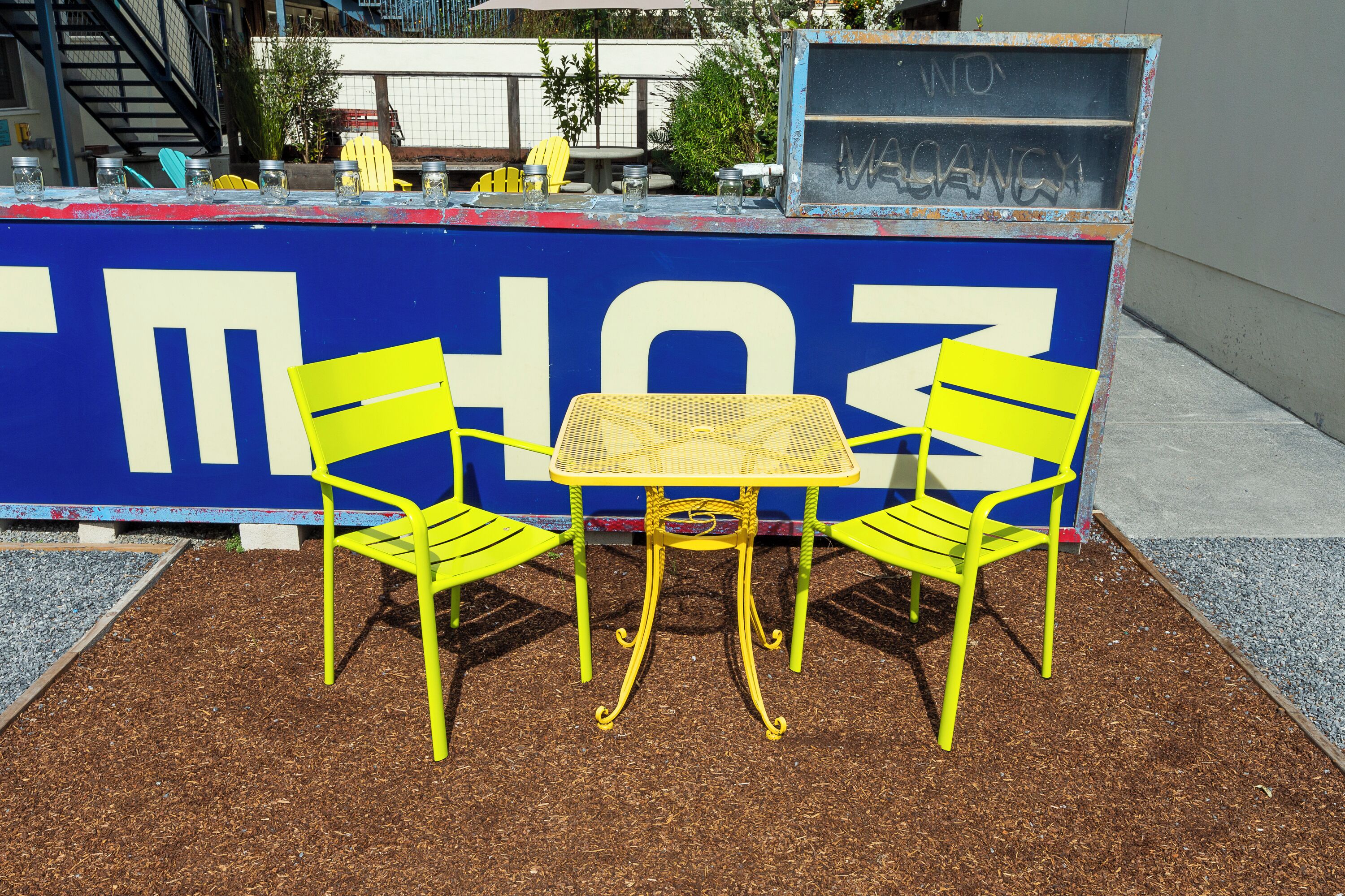 Un cartello blu e bianco con il numero 103, un tavolo giallo e due sedie gialle di fronte.
