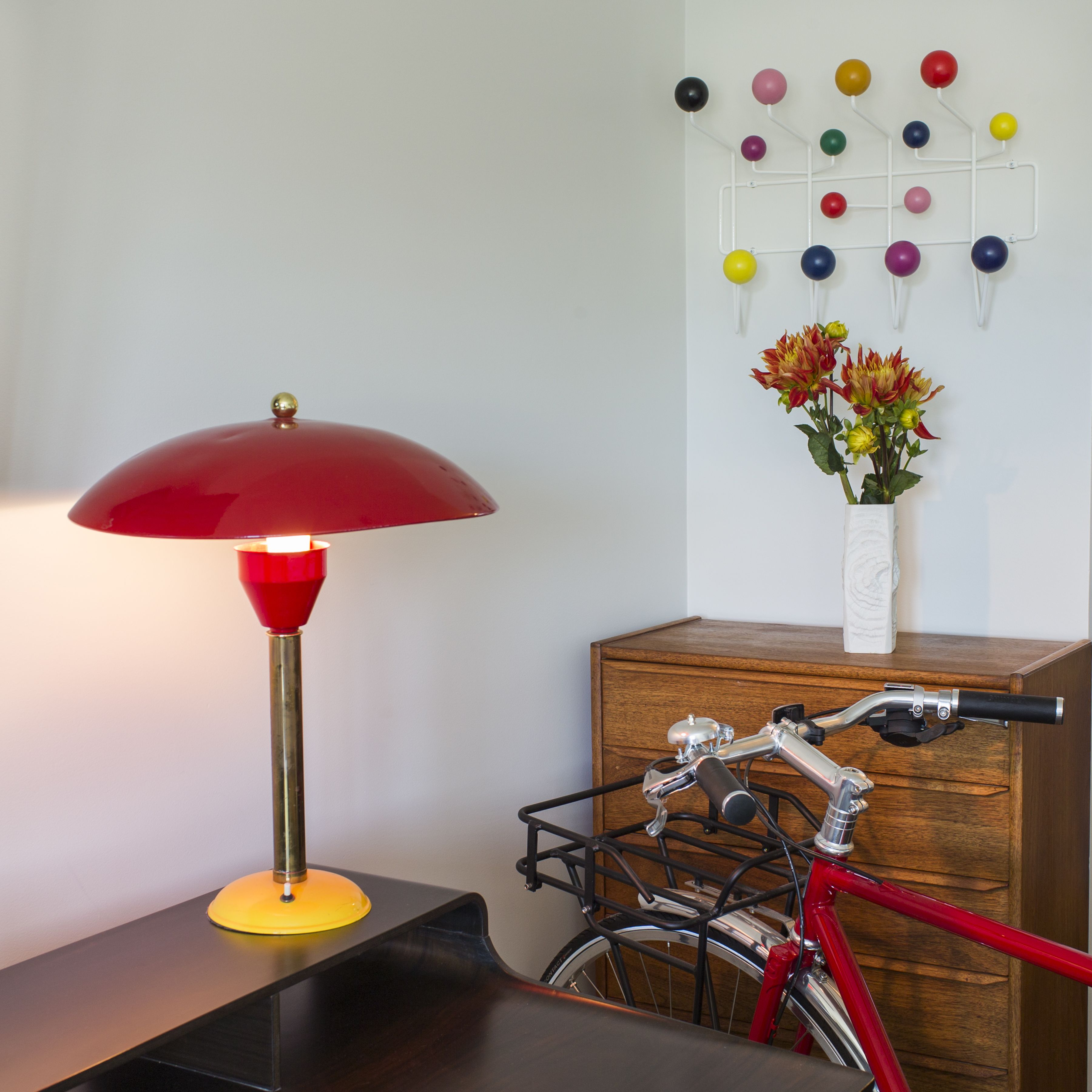 Une pièce avec une lampe rouge, un meuble en bois, un vélo et un élément décoratif mural.