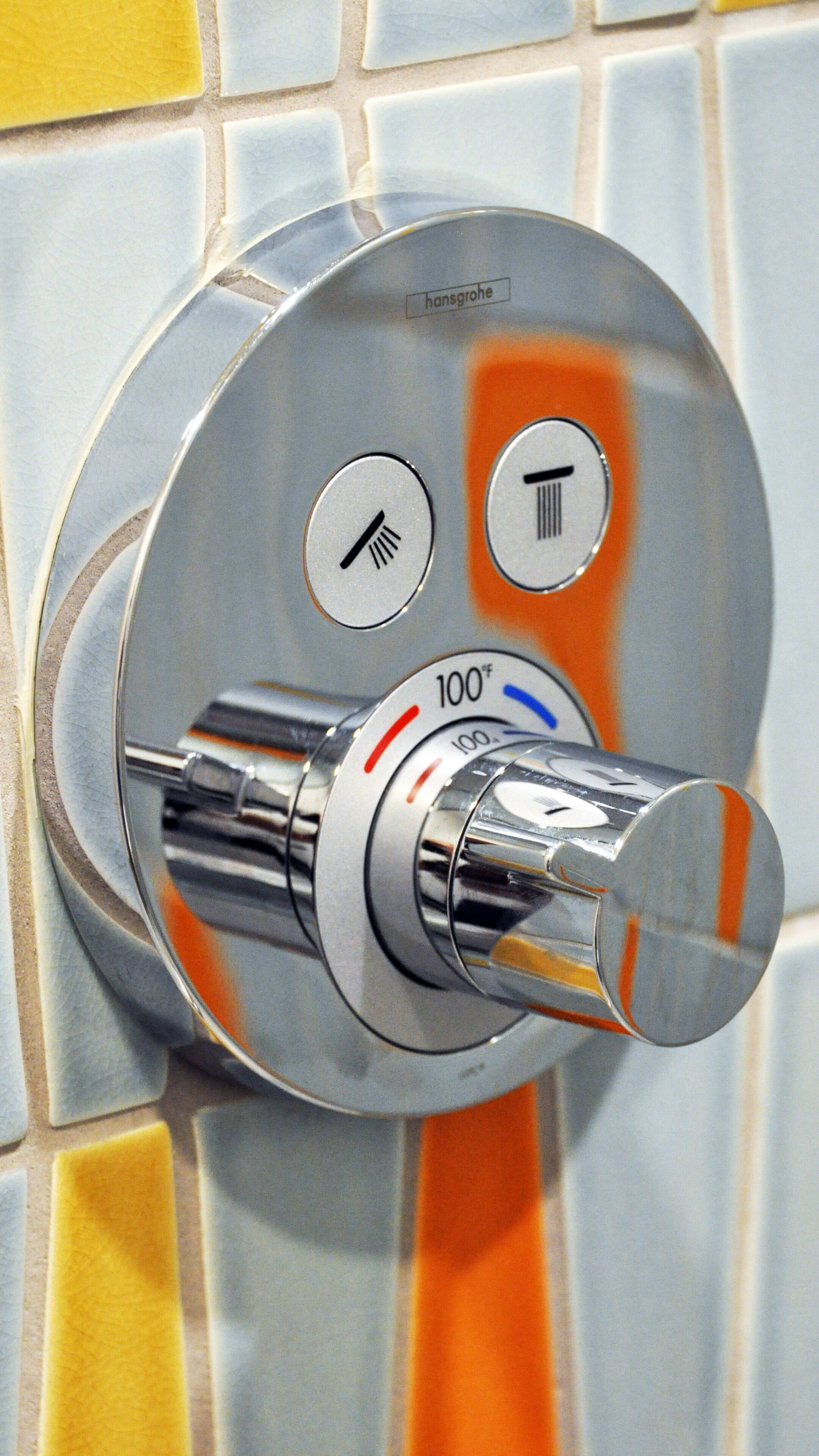 Un rubinetto da bagno con un comando a manopola per la regolazione della temperatura e icone che indicano acqua calda e acqua fredda.