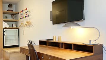 A modern kitchen with a wooden table, a chair, a TV, and a refrigerator.