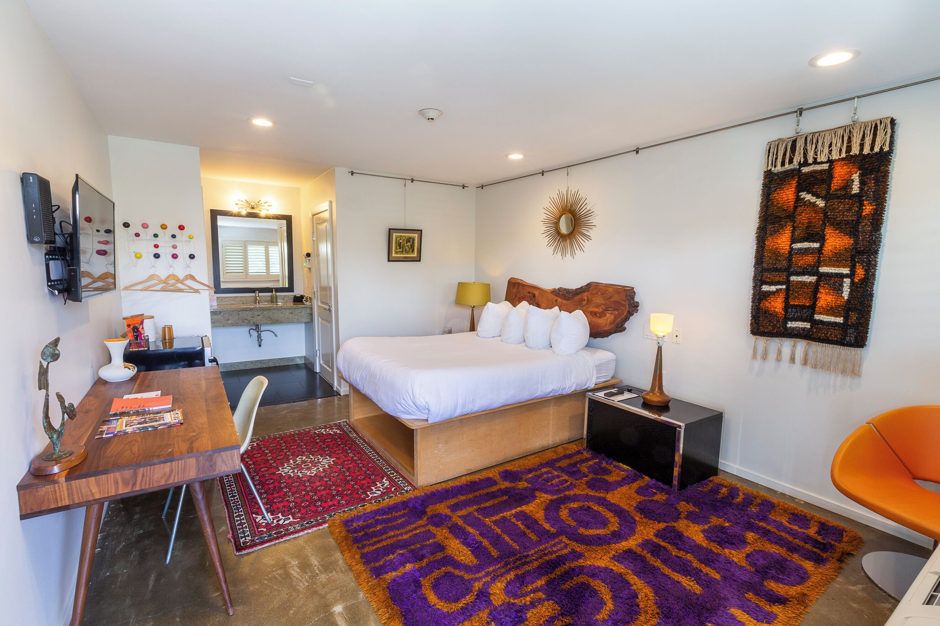 Un dormitorio moderno con cama, mesita de noche, lámpara y alfombra decorativa.