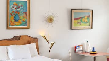 Une chambre d’hôtel avec un lit, un bureau et deux tableaux au mur.