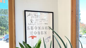 A framed poster on a wall with text and a hammer illustration, surrounded by potted plants.