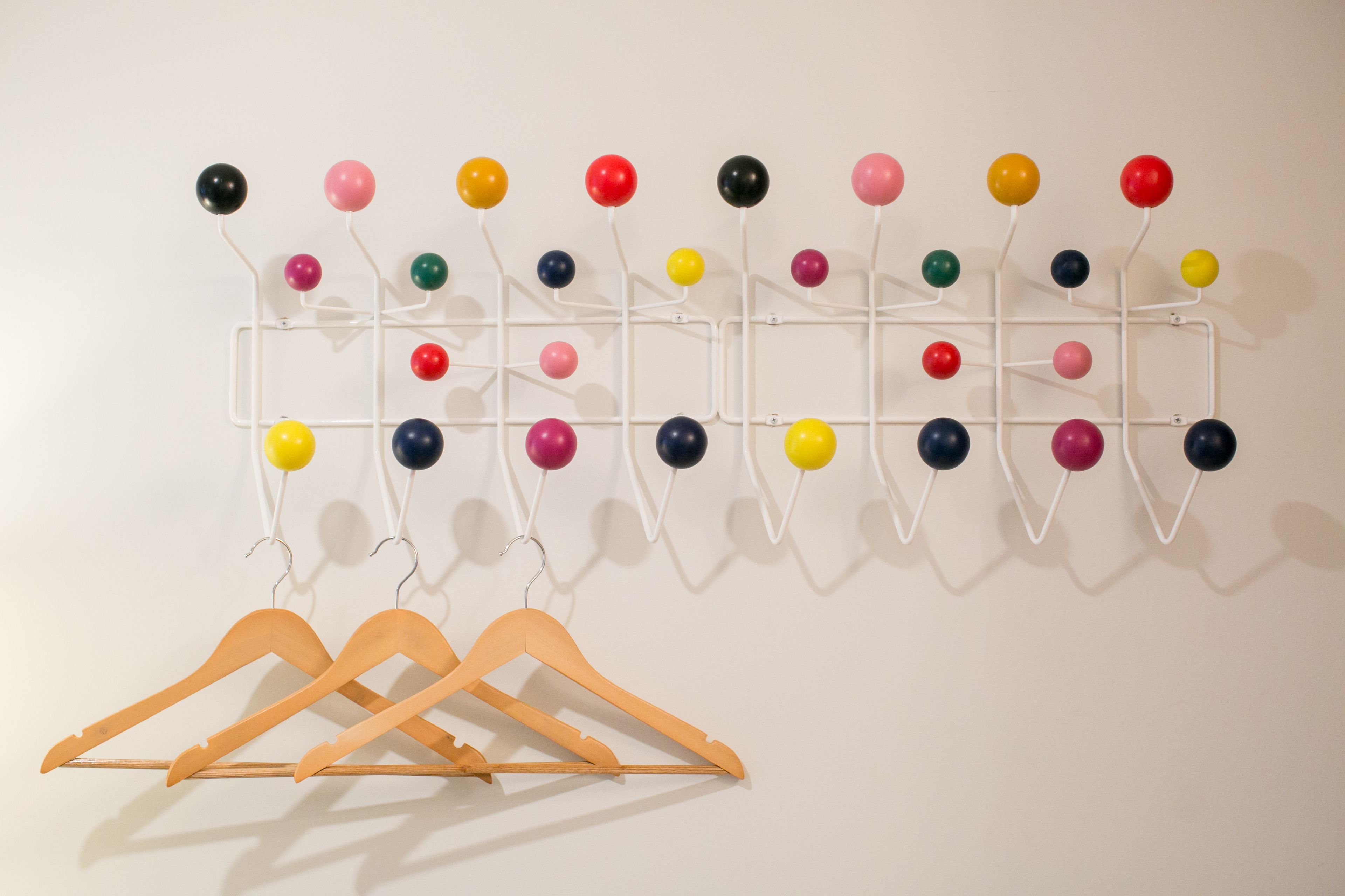 A wall-mounted rack with multiple colored balls and wooden hangers.