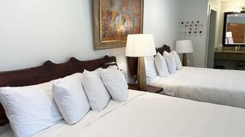 Une chambre d’hôtel avec deux lits, un tableau au mur et un miroir au-dessus du lit.
