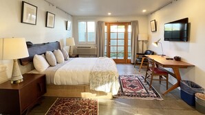 A hotel room with a bed, desk, chair, TV, and a view of the outdoors. - The Astro (Santa Rosa)