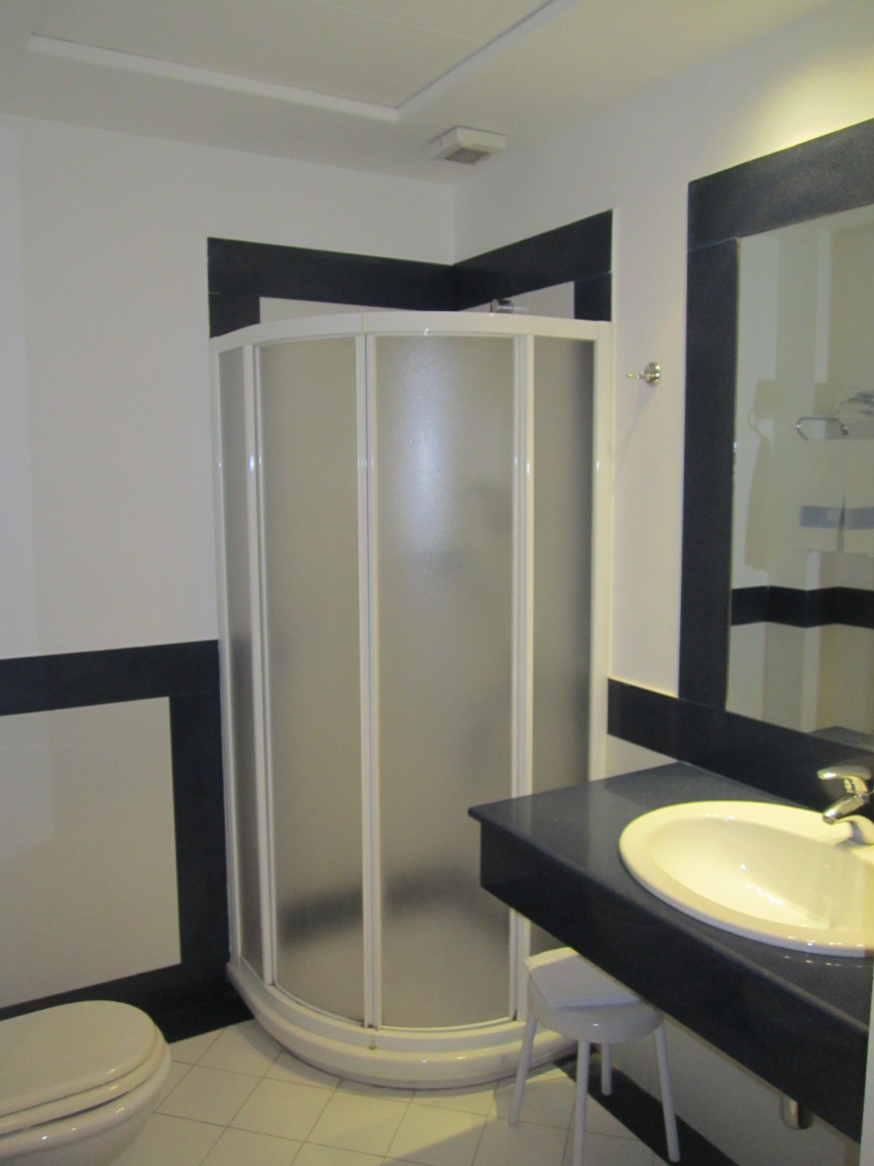 Ein Badezimmer mit Toilette, Waschbecken, Duschkabine und einem Spiegel über dem Waschbecken.