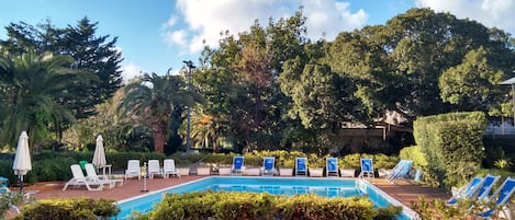 Una piscina al aire libre, sillones reclinables de piscina