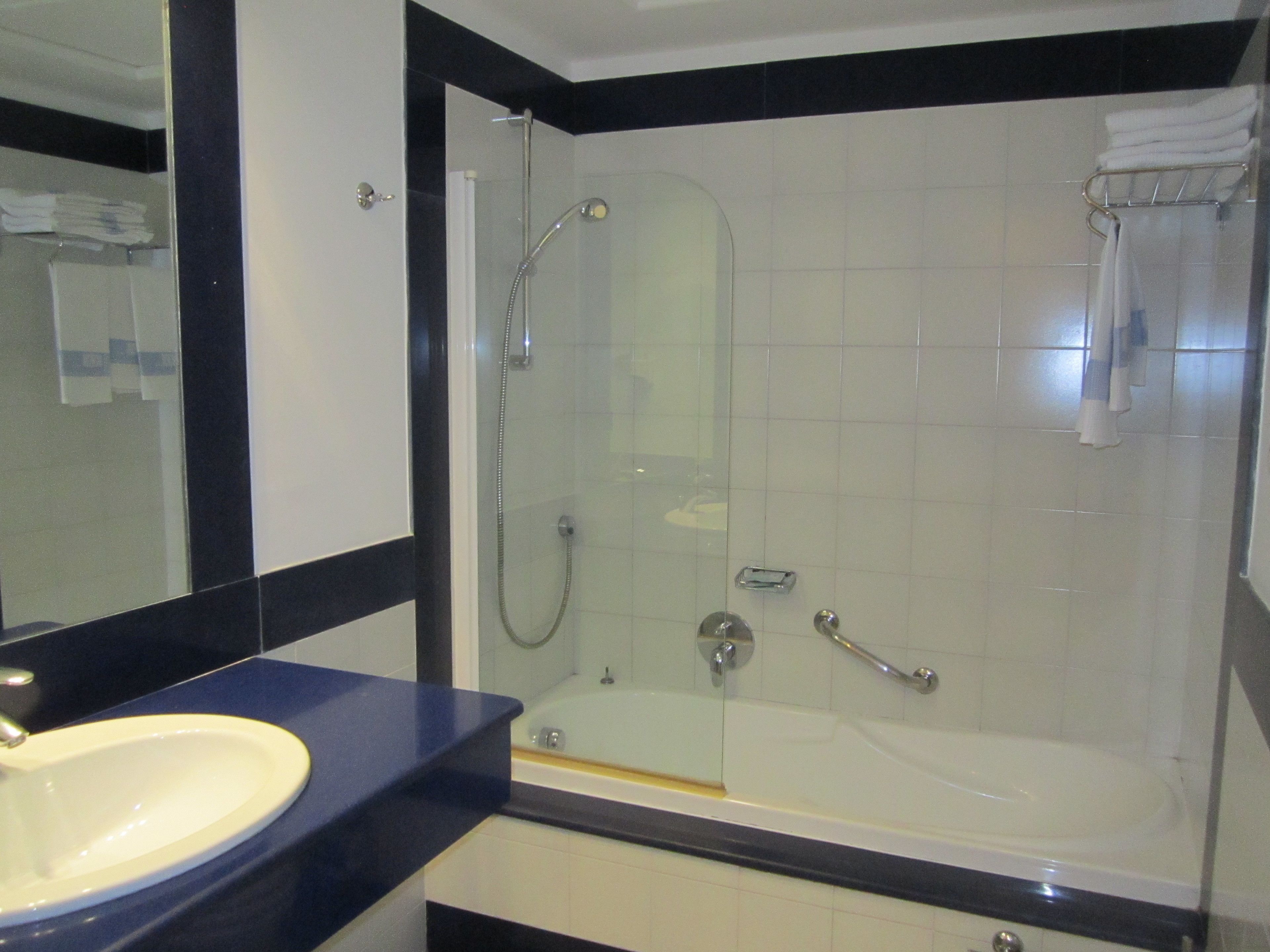 Une salle de bain moderne avec une douche à parois de verre, une baignoire blanche et un lavabo doté d’un plan de travail foncé.