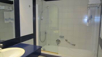 A modern bathroom with a glass-enclosed shower, a white bathtub, and a sink with a dark countertop.
