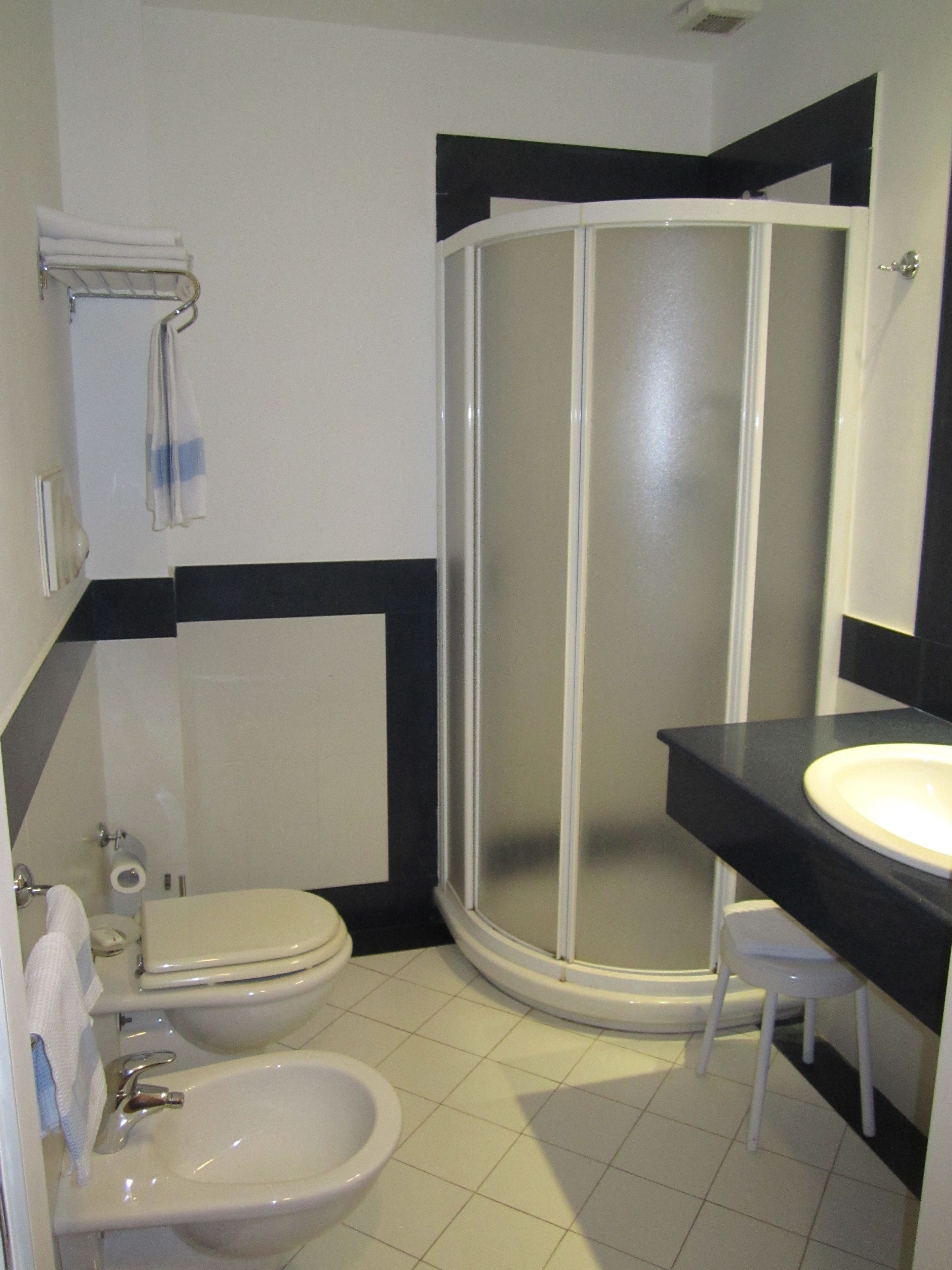A bathroom with a toilet, bidet, sink, and a glass-enclosed shower stall.