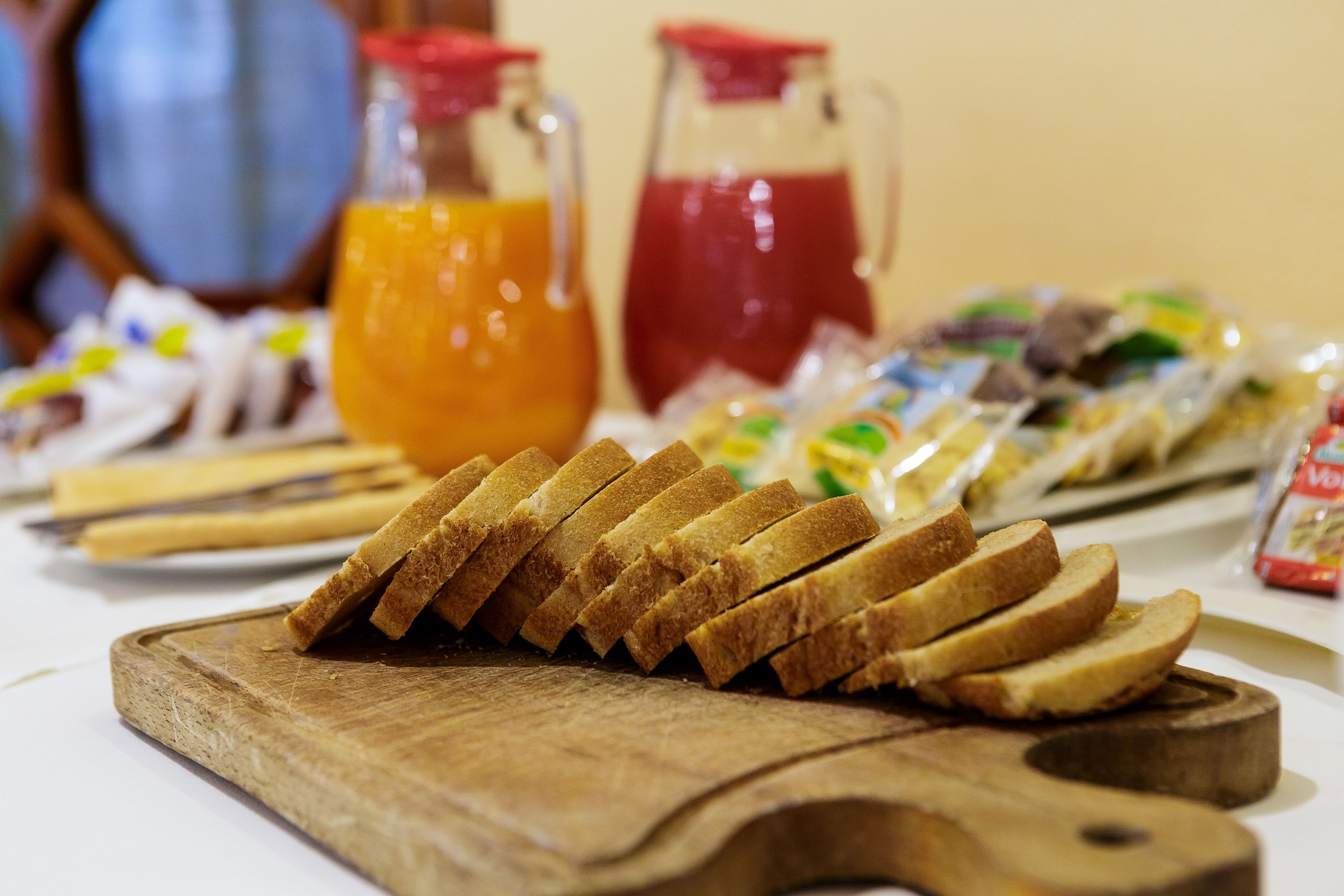 Ein Tisch mit Brot, Orangensaft und einem Krug rotem Getränk.